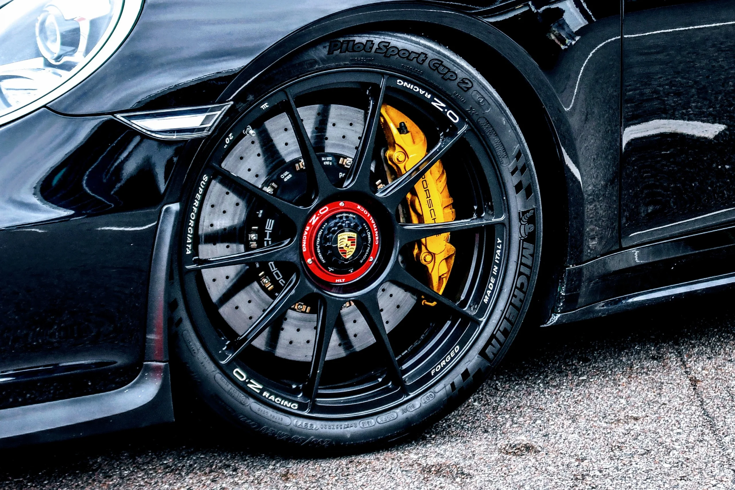 Close up of Michelin Pilot Sport Cup 2 tire on a black Porsche 911 with OZ center-lock wheels