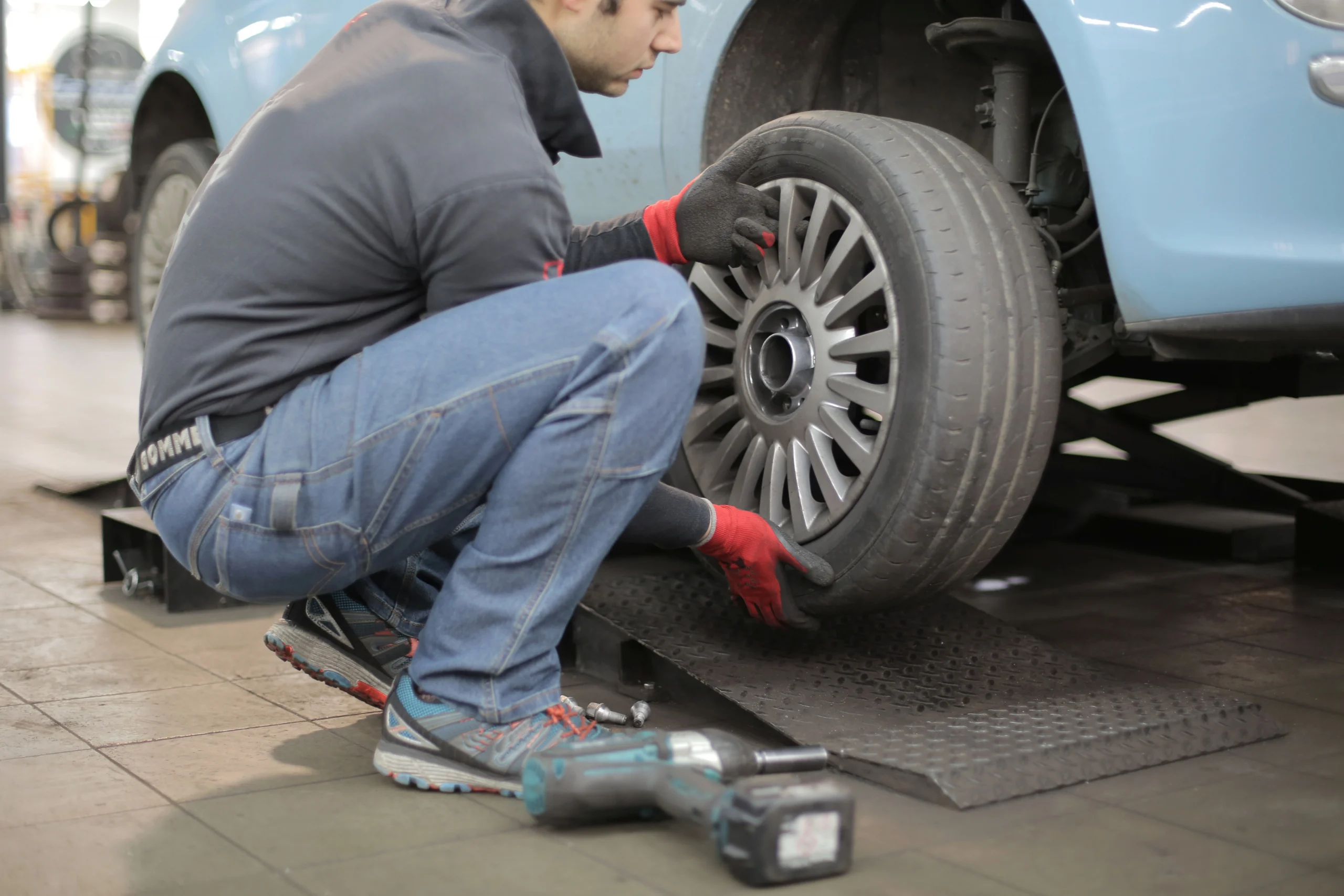 Man installing tire onto blue car