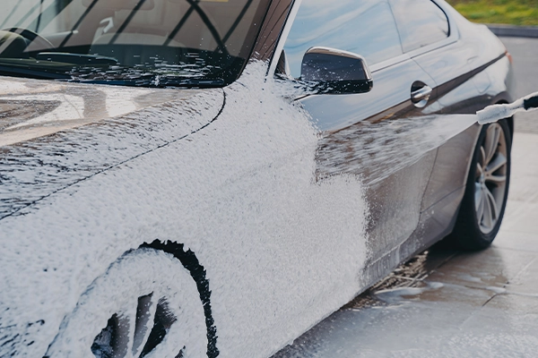 Black BMW being washed with soap and power washer